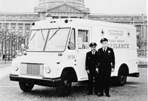 Two uniformed San Francisco Department of Public Health ambulance attendants standing beside their ambulance in front of San Francisco City Hall